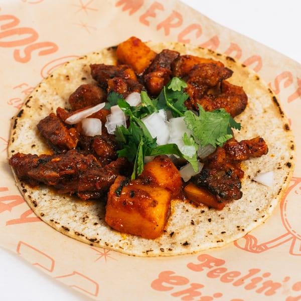 Chido Taco's al pastor taco with marinated pork, pineapple, onions, and cilantro on a corn tortilla.