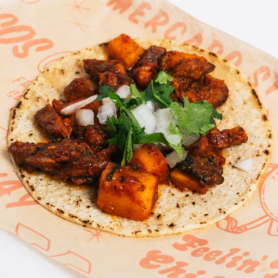 Chido Taco's al pastor taco with marinated pork, pineapple, onions, and cilantro on a corn tortilla.